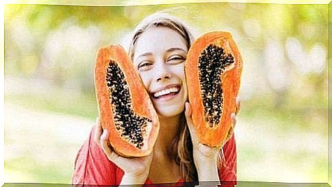 Woman posing with a papaya cut in half